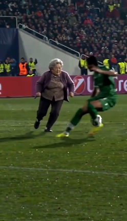 At seven seconds, a green-shirted defender crosses in front of the woman in a purple cardigan and dark trousers.